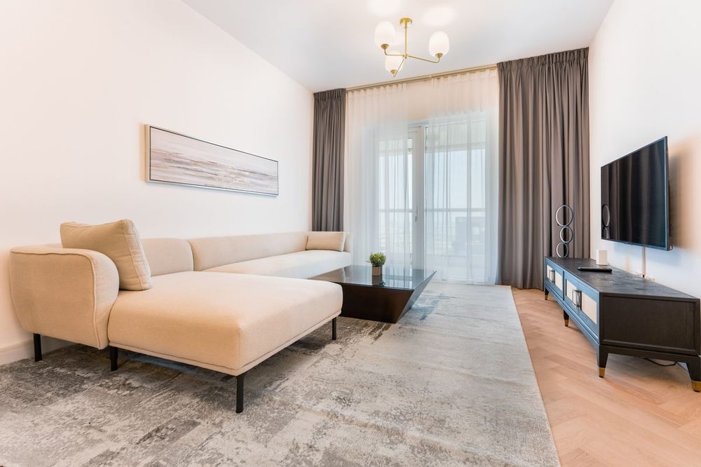 Sala con alfombra y sofá de tela en tonos neutros, resultado de limpieza profesional de alfombras y tapetes