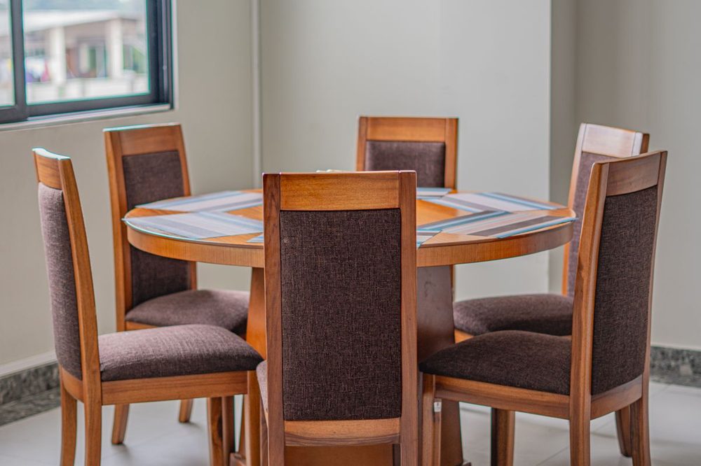 Mesa de comedor con sillas tapizadas en tela café, listas para limpieza profesional a domicilio