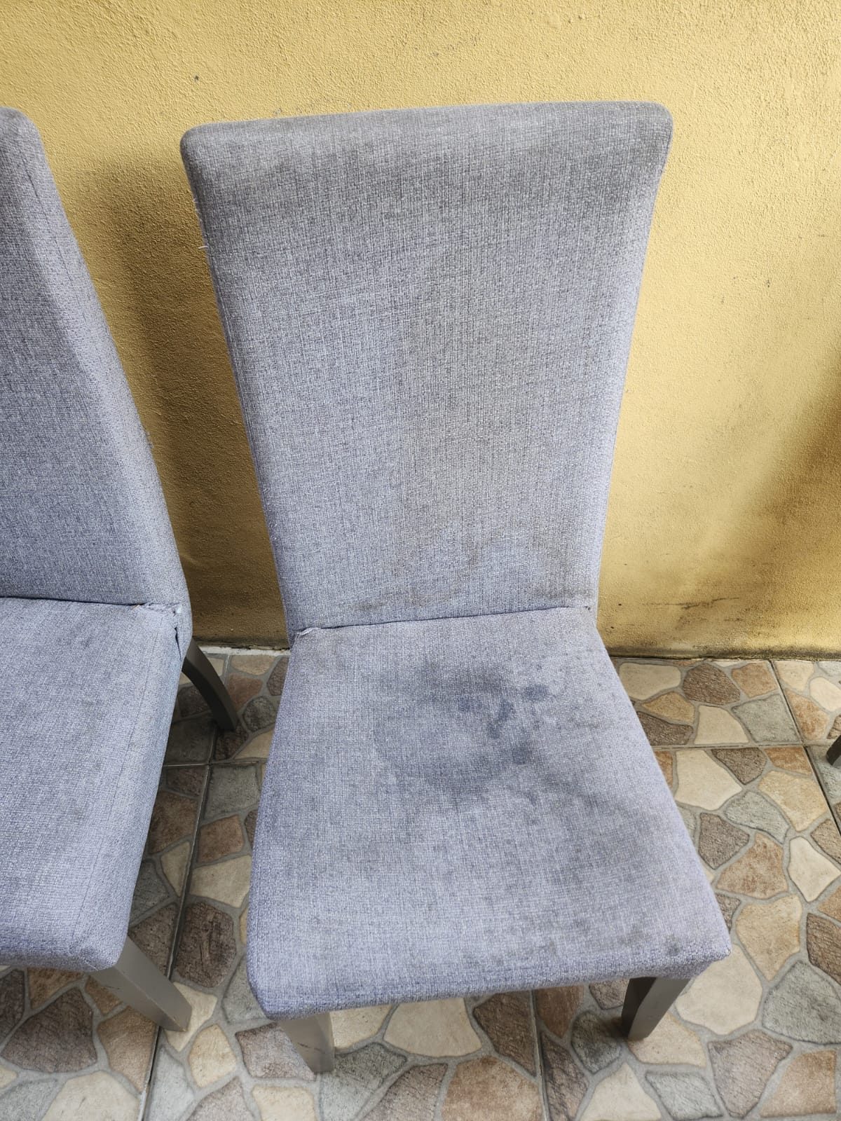 Silla de comedor tapizada en tela gris con mancha visible antes de limpieza profesional en CDMX